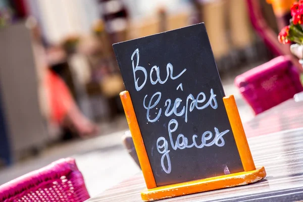 Small black board menu indicating bar, ice-creams and pancakes ("Bar Crepes Glaces" in French) on a table outside — Stock Photo, Image