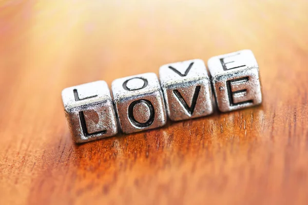 Das Wort Liebe windet sich mit Metallbügeln über altem Holzhintergrund — Stockfoto