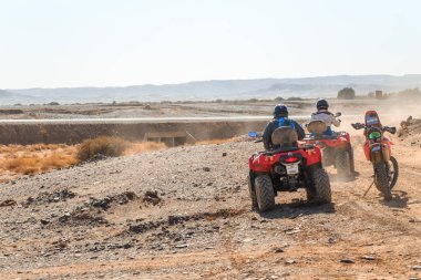 Dörtlü ATV Sahara Çölü'nde üzerinde iki bisikletçi.