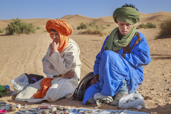 Nomad vendors of the Sahara desert, sitting in the sand selling souvenirs.
