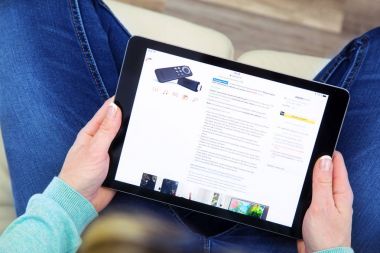 Benon, Fransa - 21 Ocak 2018: bağdaş kurup ürünleri Amazon Web sitesinde görmek için bir dokunmatik yüzey kullanarak onun kanepede oturan kadın. Amazon.com, Inc olan Seattle'da bir Amerikan e-ticaret şirketi kim satış kültürel ürünler her türlü.