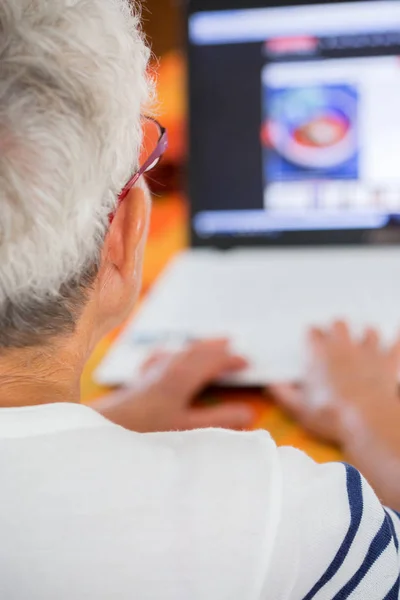 Seniorin mit Brille vor Laptop — Stockfoto