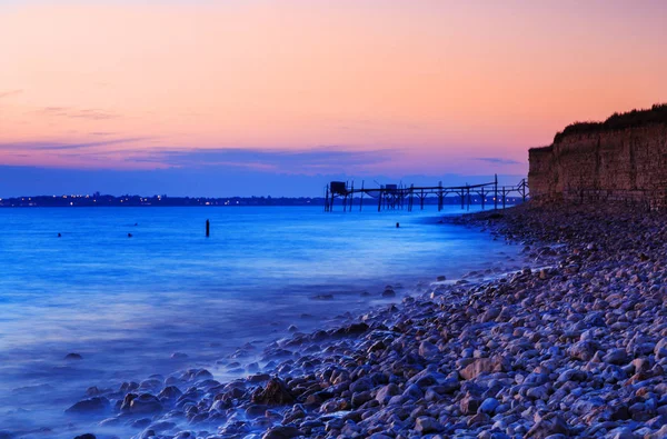 Sunset on the seashore with fishing huts in background — Stock Photo, Image