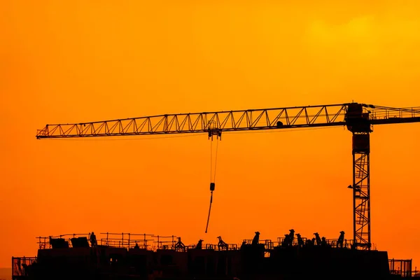 Travailleurs du bâtiment travaillant sur un bâtiment sous un coucher de soleil — Photo