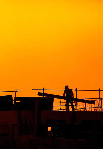 Trabajadores de la construcción que trabajan en un edificio bajo una puesta de sol — Foto de Stock