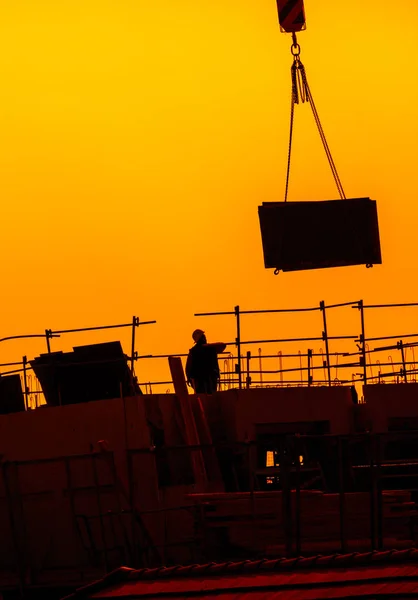 Lavoratori edili che lavorano su un edificio sotto un tramonto — Foto Stock