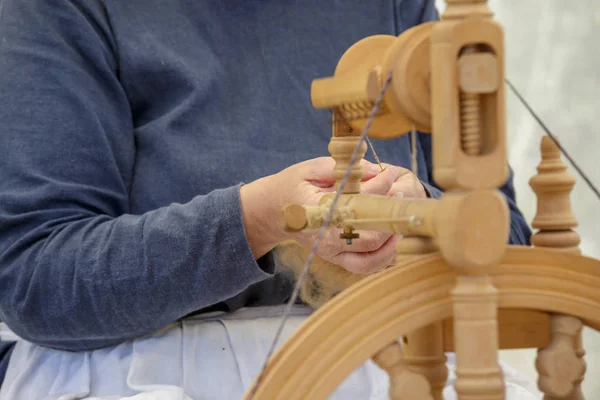 Oude vrouw met behulp van een oude wol spinnewiel — Stockfoto