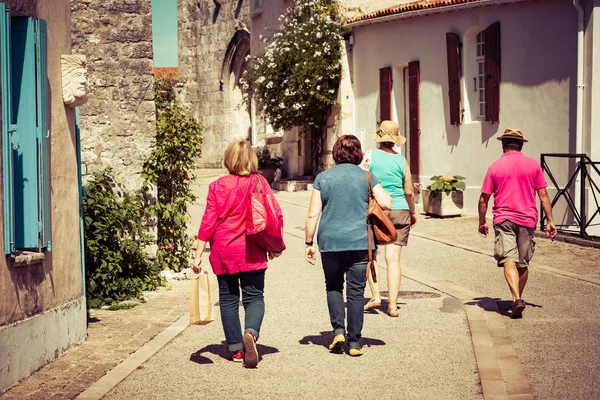 Visão traseira de um grupo de turistas que caminham em uma aldeia no verão — Fotografia de Stock