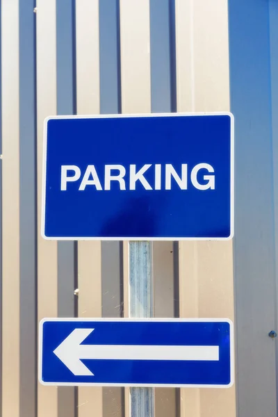 Blue sign with white lettering - "Parking" and showing a left po — Stock Photo, Image