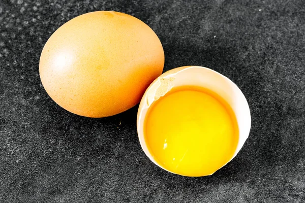Uovo fresco rotto nel guscio con un uovo intero su un dorso vintage — Foto Stock