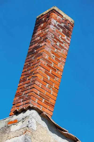 Brown brick chimney on rooftop of domestic house against blue clear sky