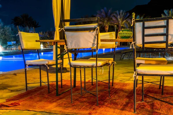 Mesa y silla cerca de piscina swimmimg por la noche — Foto de Stock