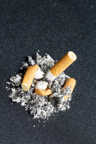 Pila de cigarrillos fumados en una pila de cenizas — Foto de Stock