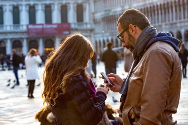 Baba ve kızı eski meydanda akıllı telefon kullanıyor.
