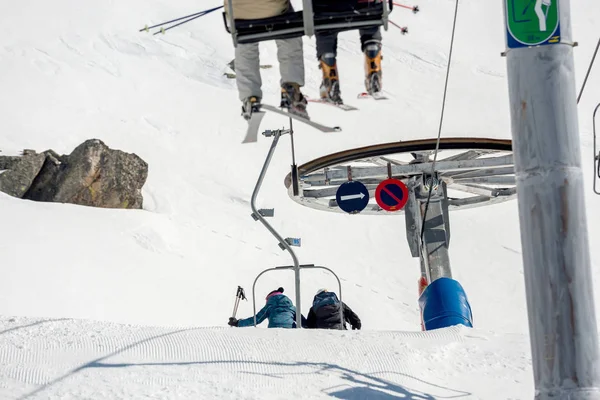 Nierozpoznane osoby jadące kolejką górską po śnieżnym zboczu góry — Zdjęcie stockowe