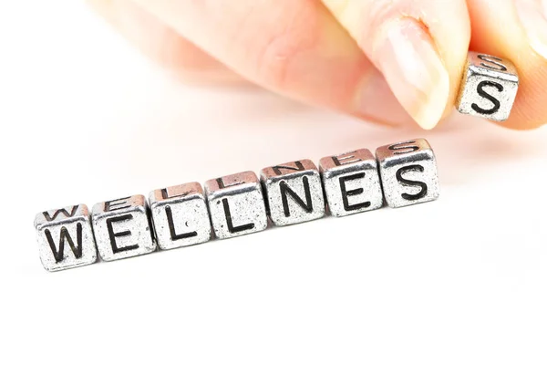 Wellness concept with cube letters and a woman hand placing a letter — Stock Photo, Image