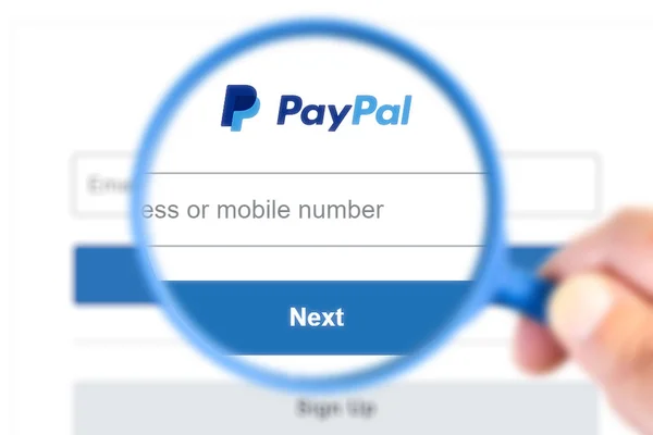 Formulário de login Paypal com logotipo ampliado com uma lupa . — Fotografia de Stock