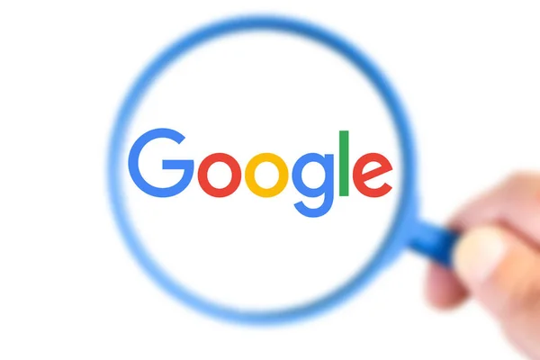 Google logotype enlarged with a magnifying glass — Stock Photo, Image