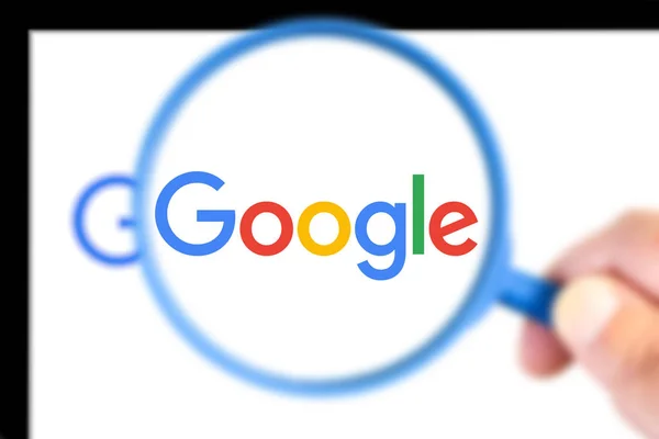 Логотип Google увеличен увеличительным стеклом — стоковое фото