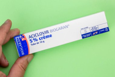 Aciclovir tüpüne yakın çekim. 5pc yeşil arkaplanda el ele tutuştu.
