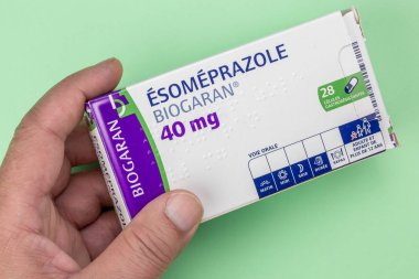 Esomeprazole kutusu yeşil bir arka planda el ele tutuştu