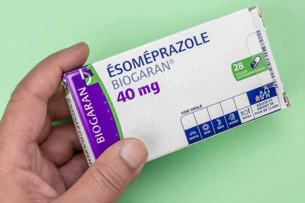 Esomeprazole box held in hand on a green background — ストック写真