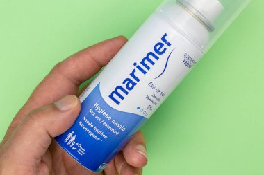 Yeşil arka planda el ele tutulan Marimer şişesine yakın plan.