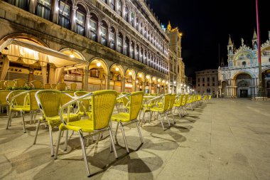 Venedik, İtalya - 19 Mart 2015: San Marco Meydanı 'nın gece manzarası ünlü bir bara ait çok sayıda boş sandalye gösteriyor. Meydanda terk edilmiş başka turist kalmadı.