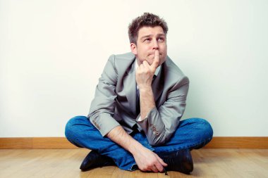 Evde bacak bacak bacak üstüne atmış endişeli ya da endişeli bir adamın portresi.