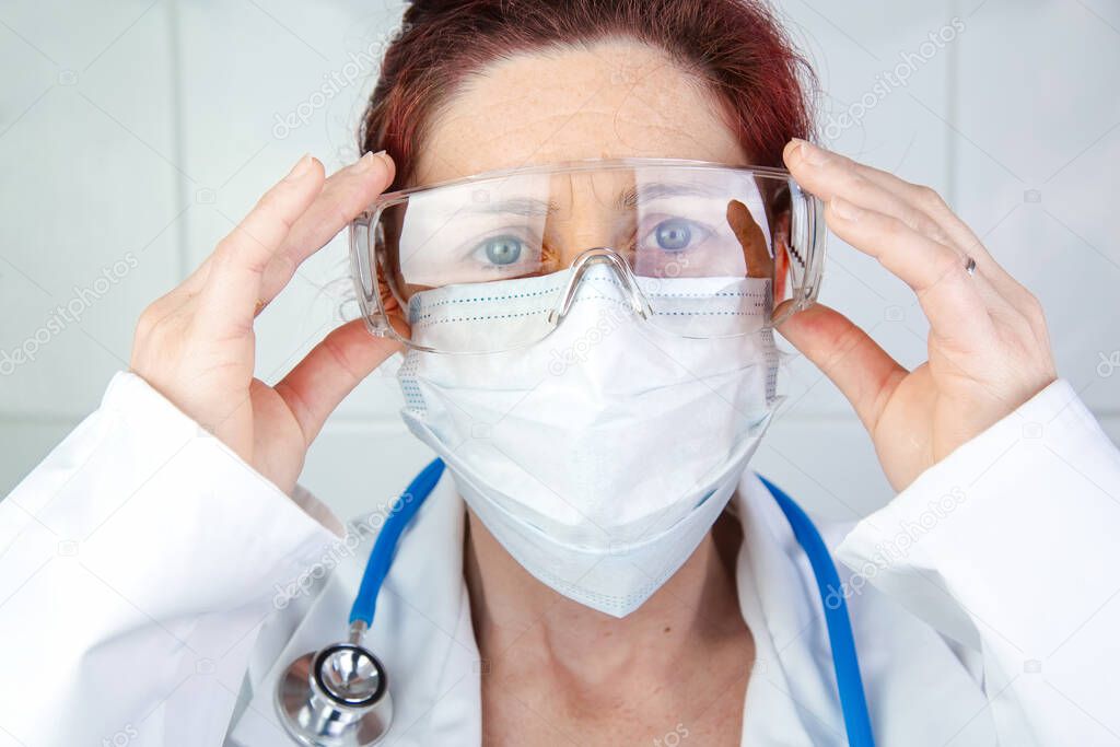 Close-up portrait of a nurse or doctor adjusting her protective glasses