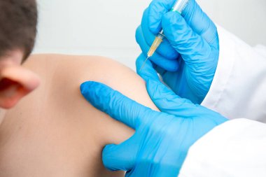 Hastanede bir çocuğa aşı yapan bir hemşirenin yakın plan portresi.