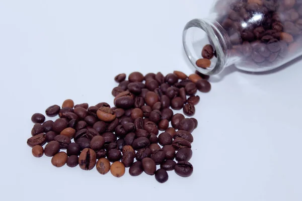 ハートの形をしたコーヒー豆ガラス瓶から撒かれたコーヒー豆コーヒーの愛 — ストック写真