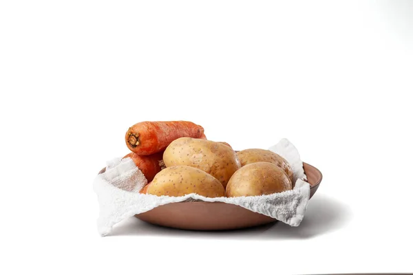 Havlunun üzerinde havuç ve patates kaynatılmış beyaz arka planda bir tabakta.