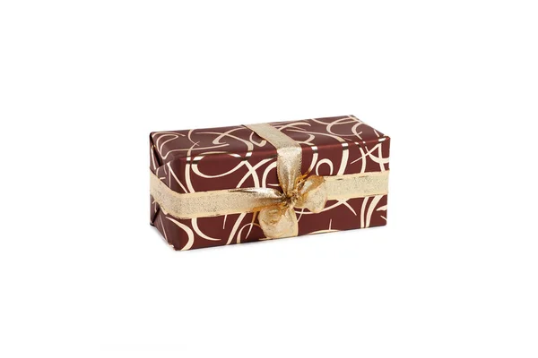 Csomagolt téglalap alakú ajándék sötétbarna csomagolásban arany íjjal és arany mintával fehér alapon — Stock Fotó