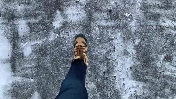 Vista dall'alto: i piedi degli uomini scendono lungo la strada in inverno. Pov ha sparato a un uomo con stivali marroni e jeans blu passeggia per la città in inverno. Inverno russo . — Video Stock