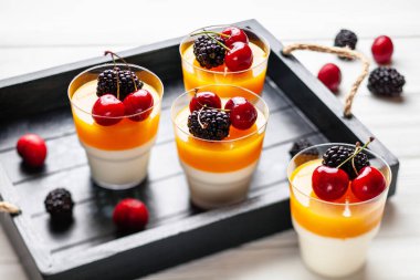 Tahta tepside böğürtlen ve kirazlı 4 bardak mango pannacota.