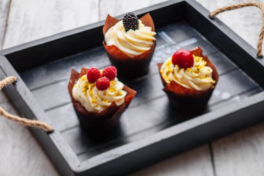 muffins with Belgian chocolate and white chocolate cream and mascarpone with berries on a wooden tray