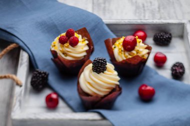 muffins with Belgian chocolate and white chocolate cream and mascarpone with berries on a wooden tray