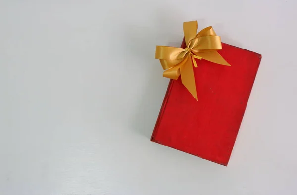 Yüksek açılı klasik kapaklı kırmızı kitap beyaz masaya yerleştirilmiş altın fiyonk 