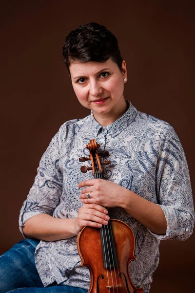 Beautiful woman with violin on dark brown background