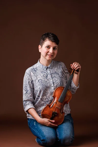 Beautiful woman with violin on dark brown background