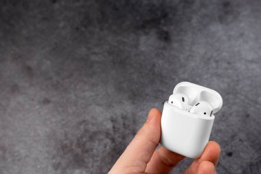 Adam hava kapsüllerini elinde tutuyor. Hava kapsülleri. Kablosuz şarj davasıyla. Kazı metal arka planda yeni hava araçları. Hava podları. Boşluğu kopyala