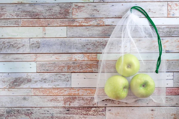 Eco bag with green apple. Concept of eco-friendly materials. Close up. Copy space. light wood background