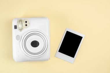 Modern polaroid kamera, sarı arka plan. Üst manzara, yumuşak minimum düz konum kompozisyonu. moda blogcusu, güzellik teknolojisi