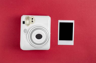 Modern polaroid kamera, kırmızı arka plan. Üst manzara, yumuşak minimum düz konum kompozisyonu. moda blogcusu, güzellik teknolojisi