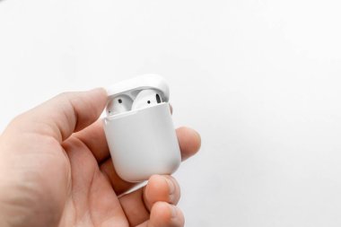 Hava kapsülleri. Kablosuz şarj davasıyla. Yeni hava araçları 2019 beyaz masada. Hava podları. Adamın elinde kulaklık var.