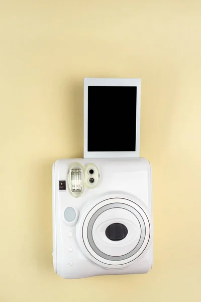 Modern polaroid camera, yellow background. Top view, tender minimal flat lay style composition. fashion blogger, beauty technology