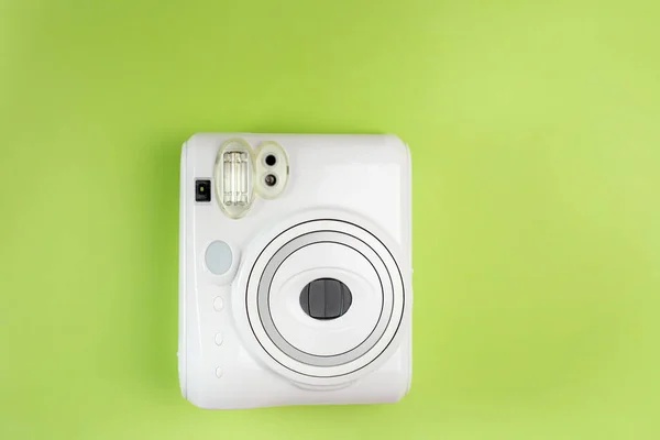 Modern polaroid camera, green background. Top view, tender minimal flat lay style composition. fashion blogger, beauty technology