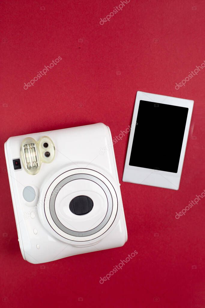 Modern polaroid camera, red background. Top view, tender minimal flat lay style composition. fashion blogger, beauty technology