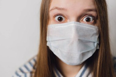 Kız beyaz bir arka plana tıbbi maske takıyor. Corona virüsünün önlenmesi. Corona virüsünün önlenmesi. Biyolojik koruma salgını salgını konsepti bilim adamı. COVID-19